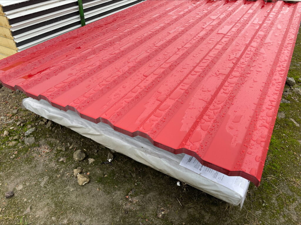 Czerwone panele metalowe na budowie, mokre po deszczu.